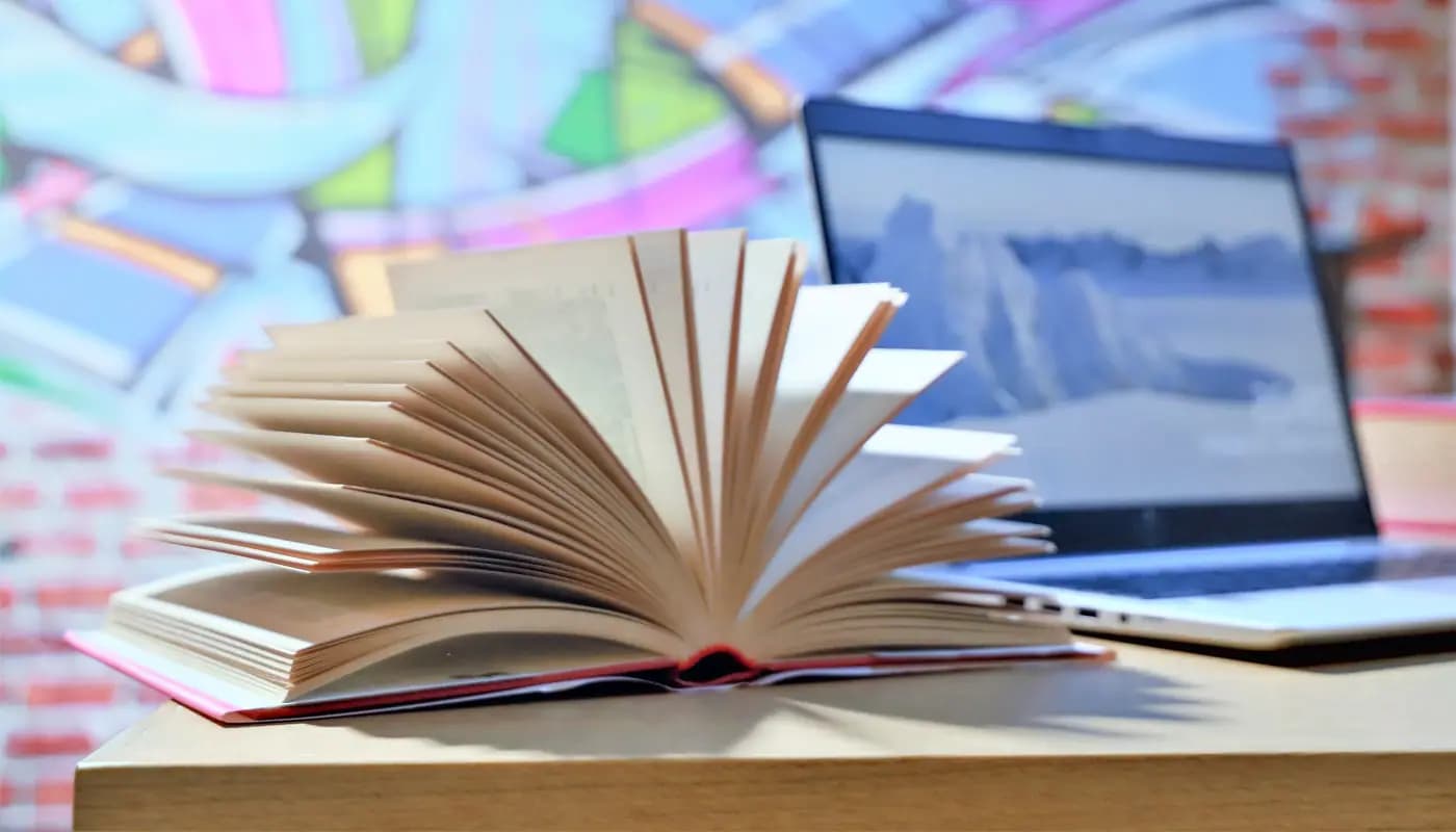 Publishing desk with manuscript pages, book layout software, and finished paperbacks